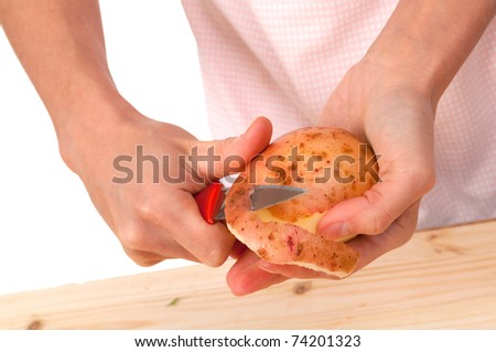 Hand holding knife peeling potato vegetable food .Studio, white background.
