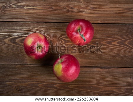 Autumn border from apples and fallen leaves on old wooden table.