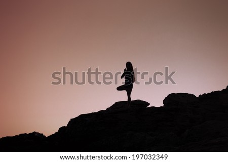 Young woman practices yoga at sunrise