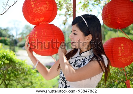 Chinese woman in traditional cheongsam holding paper lantern