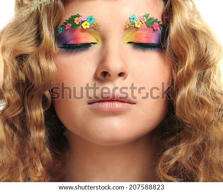 Beautiful girl with bright makeup and eyebrows decorated with flowers. Fantasy girl portrait. Summer fairy portrait. Long permed hair