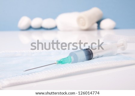 Syringe. Round Gauze Ball and Bandage on Blue Background
