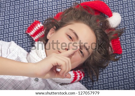 Sleepy handsome teenage boy lying on the floor with Christmas hat