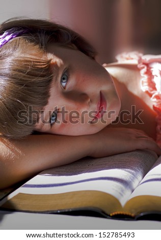 Beautiful Girl Reading Holy Bible. Sitting on a table