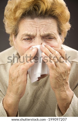 Senior woman sneezing. Using napkin