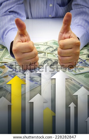 Businessman\'s hands with thumbs up over bulk of money with arrows pointing upwards showing financial growth - Financial success concept