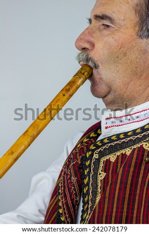Pipe player in traditional clothing. Woodwind instrument