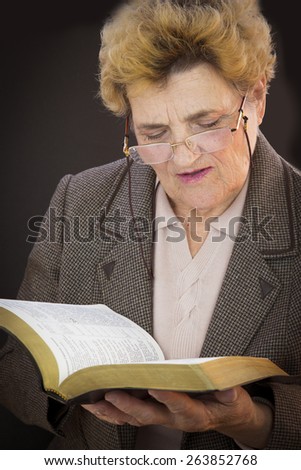 Senior woman reading holly bible. Woman with glasses. Black backgground
