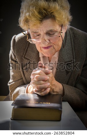Senior woman reading holly bible and praying. Woman with glasses