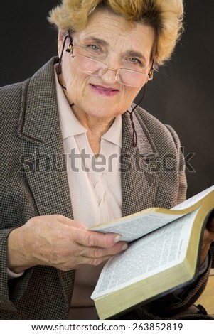 Senior woman reading holly bible. Woman with glasses. Black backgground