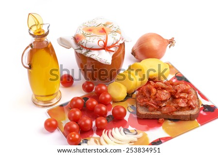 Vegetarian food.\
Still life with home canning jar of vegetable caviar and bottle of vegetable oil, cherry tomatoes, onion and potato.