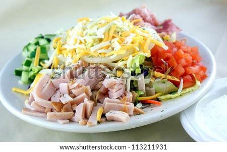 Chopped salad with turkey, ham, cucumber, tomato, iceberg lettuce, onion and cheese.