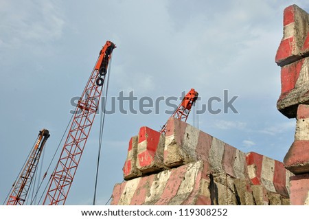 Construction Crane hook and stack of concrete barriers blocking