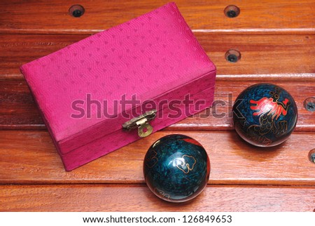 chinese hand massage balls with their pink box in wood background