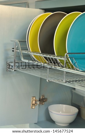 colorful plates in stainless rack within cabinet
