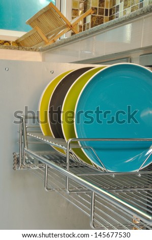colorful plates in stainless rack within cabinet