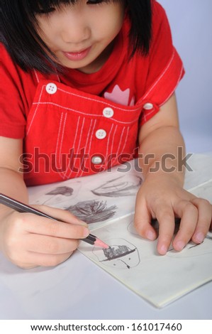 3 years old asian girl draws and sketches many human faces with pencil