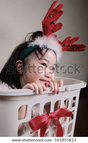 asian little girl wearing a reindeer headband in gift basket, Christmastime, New Year holiday concept