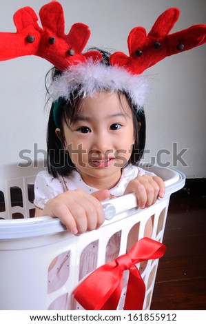 asian little girl wearing a reindeer headband in gift basket, Christmastime, New Year holiday concept