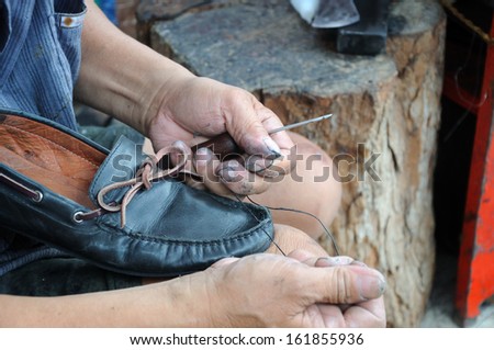 man is repairing leather shoe; an occupation in Thailand