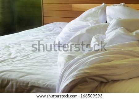 messy unmade bed with wrinkled sheets in the morning time