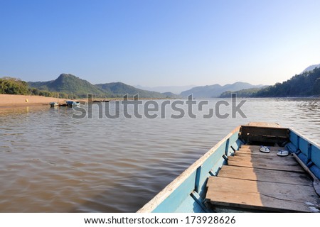 Head of wooden long tailed boat running through river in Lao