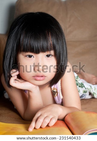 Tired asian little girl feel sleepy near her book