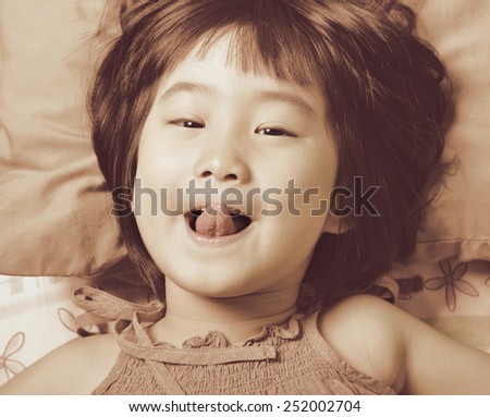 closeup cute little asian girl face while  playing in the bed in vintage style