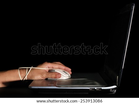 woman hand was bond with computer mouse over dark background low key, computer and internet addiction concept