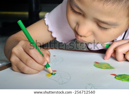closeup little asian girl hand draw her picture with color pencil