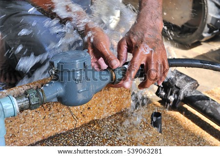 Close-up of worker hands plumbing unscrew connecting pipe while water leak, selective focus