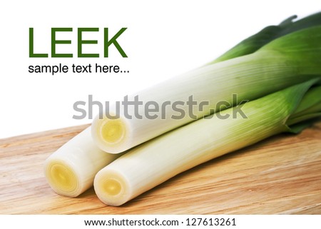 Fresh leeks whole on a wooden bread board, isolated over white background