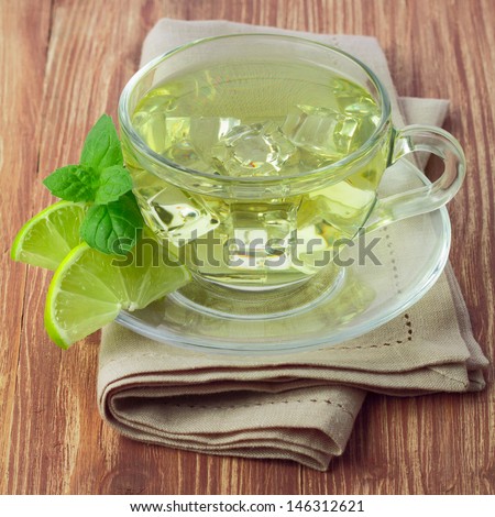 Cold green tea with ice cubes, lime sliced and mint leaves