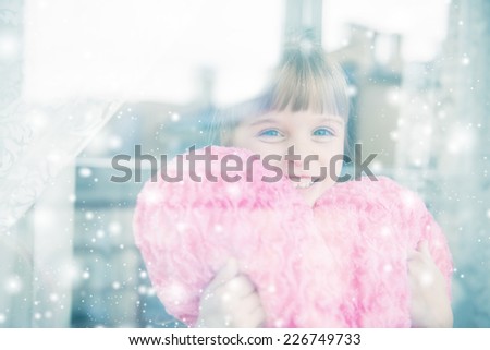 Little girl behind a window. It\'s snowing outside.