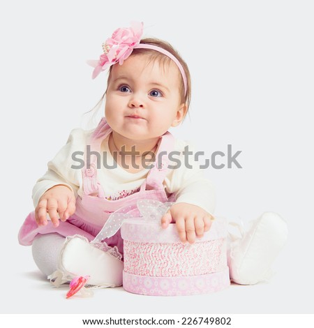 baby girl sitting on the floor with gift box and looking up baby girl sitting on the floor with gift box and looking up