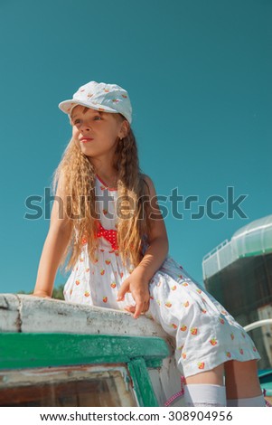 Portrait of little cute girl enjoying playing on boat on a hot sunny day