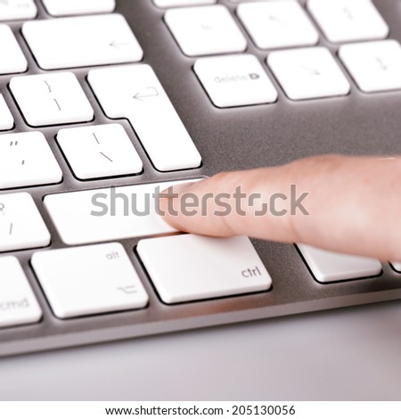 silver computer keyboard with white keys and woman finger and hand