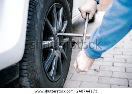 car tires prepared to replace in a garage - man hand changing tire on white car