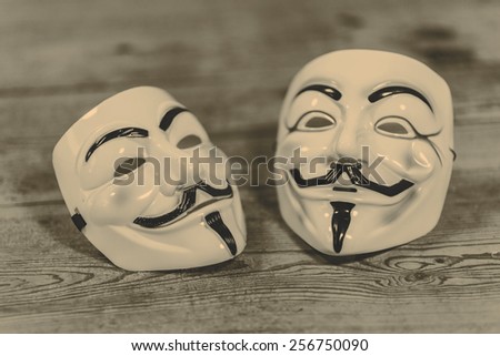 white and yellow anonymous masks on wood background - retro style