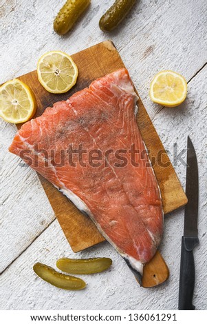 Salmon raw fish on chopping board on white wooden background