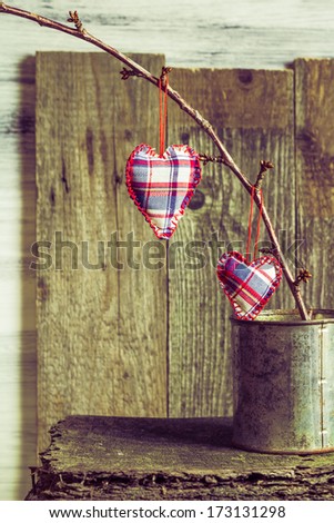 Two hearts hanging on a twig in a tin box