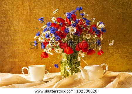 Still life with a bouquet of camomiles, cornflowers and poppies