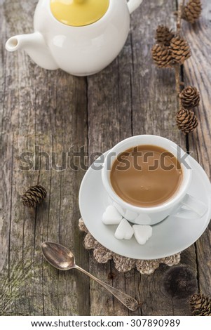 Cup of black coffee on wooden board with pines and jug