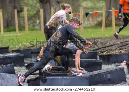 Boughton House Northamptonshire/UK-May 4, 2013: Tough Mudder challenge and obstacle course raising funds for Help for Heroes.  A participant balances on foam blocks floating on the river.