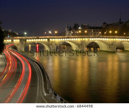 Car light trails near water and a bridge in Paris