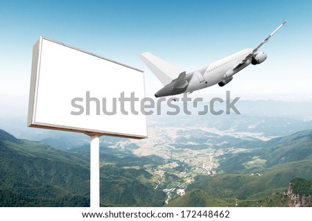Big empty billboard with copy space for your image or text with an airplane flying on the sky, ideal for travel or vacation promotions