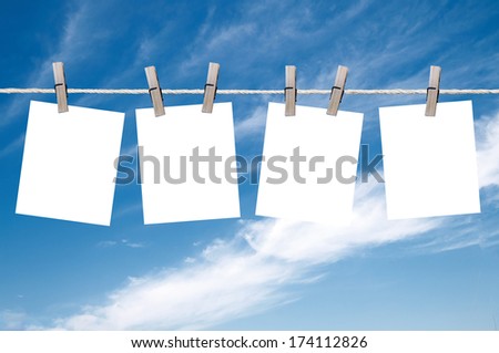 Blank pieces of paper hang on clothesline on sky background