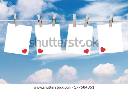 Blank pieces of paper hang on clothesline on sky background