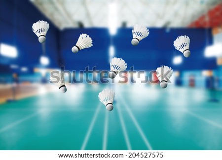 badminton - badminton courts with players competing; shuttlecocks in the foreground