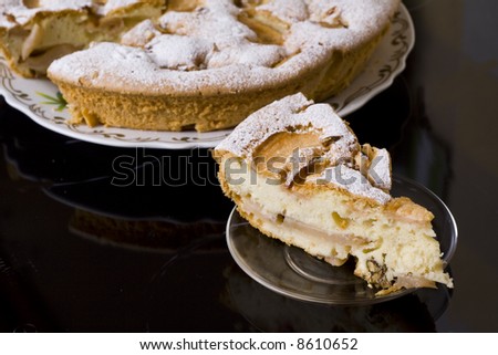 One piece of fruit pie on a saucer, the whole pie is on background. On dark background.